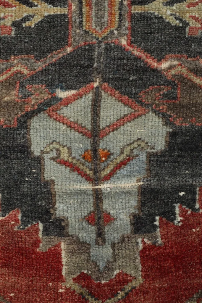 Close-up of a specific geometric motif within the rug's charcoal field, showing light blue and rust details.