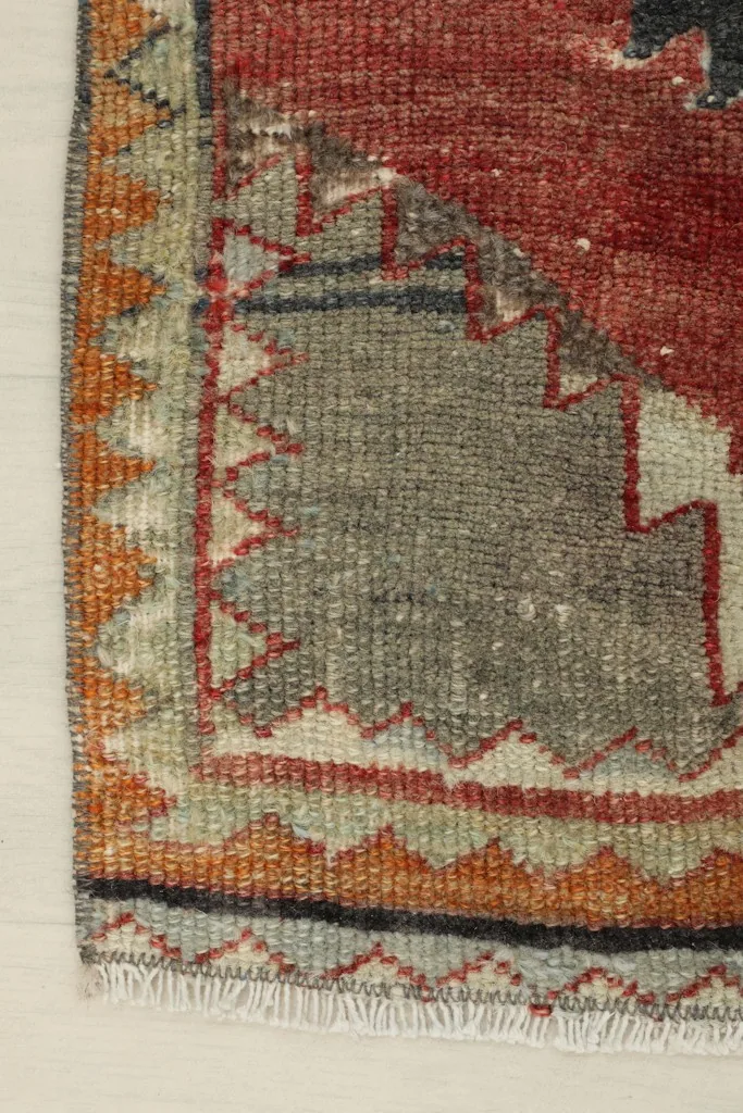 Detail of the rug's side border, featuring a blend of rust, orange, and gray colors with a serrated edge design.