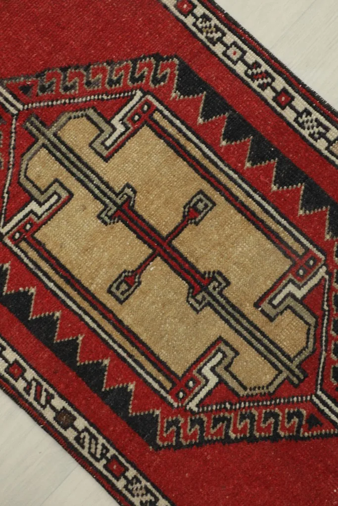 Detailed angled view highlighting the central beige geometric pattern and surrounding red field.