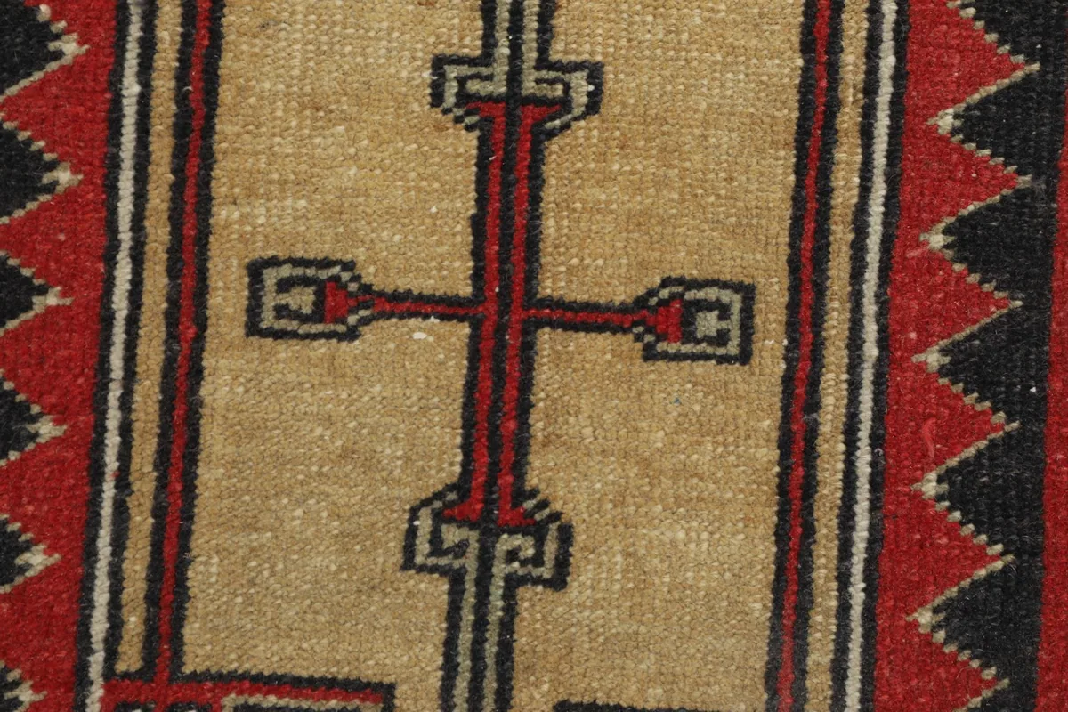 Extreme close-up of the central beige motif with red and black accents, showing knotting.