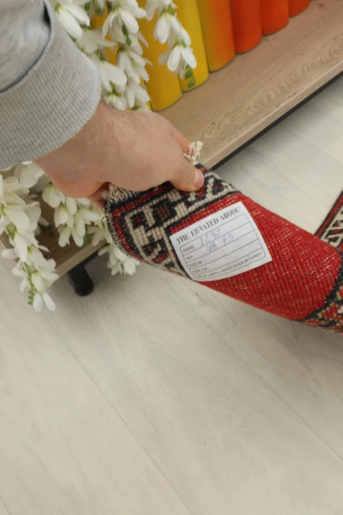 Person holding the doormat, showing the back of the rug and a label with dimensions.