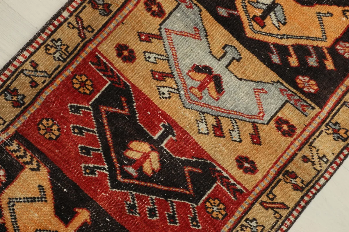 Detailed view of the rug's central motifs, showing the interplay of tan, red, and black with subtle gray.