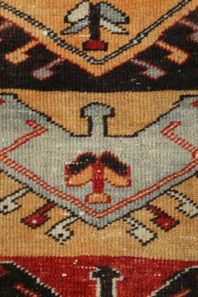 Extreme close-up of a central geometric motif, revealing the hand-knotted wool pile and color blending.
