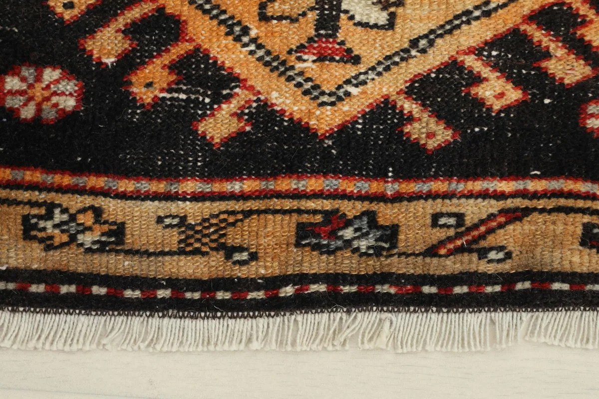 Close-up of the rug's border and fringe, highlighting the intricate details and color variations.