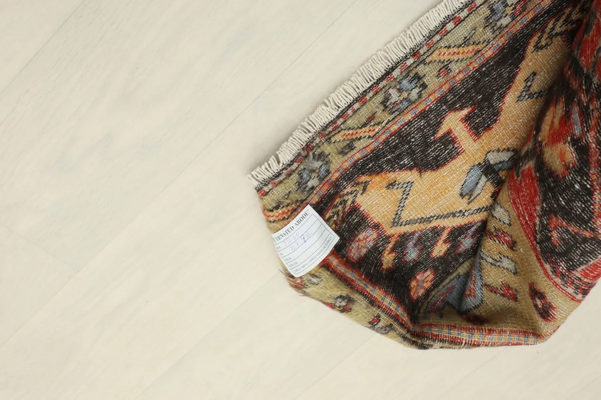View of the rug's underside and tag, showing the cotton foundation and authentic hand-knotted structure.