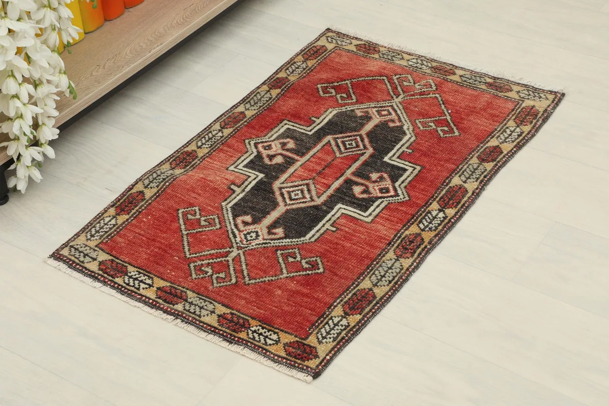 Angled view of the red vintage rug, showing its geometric design and rich colors.