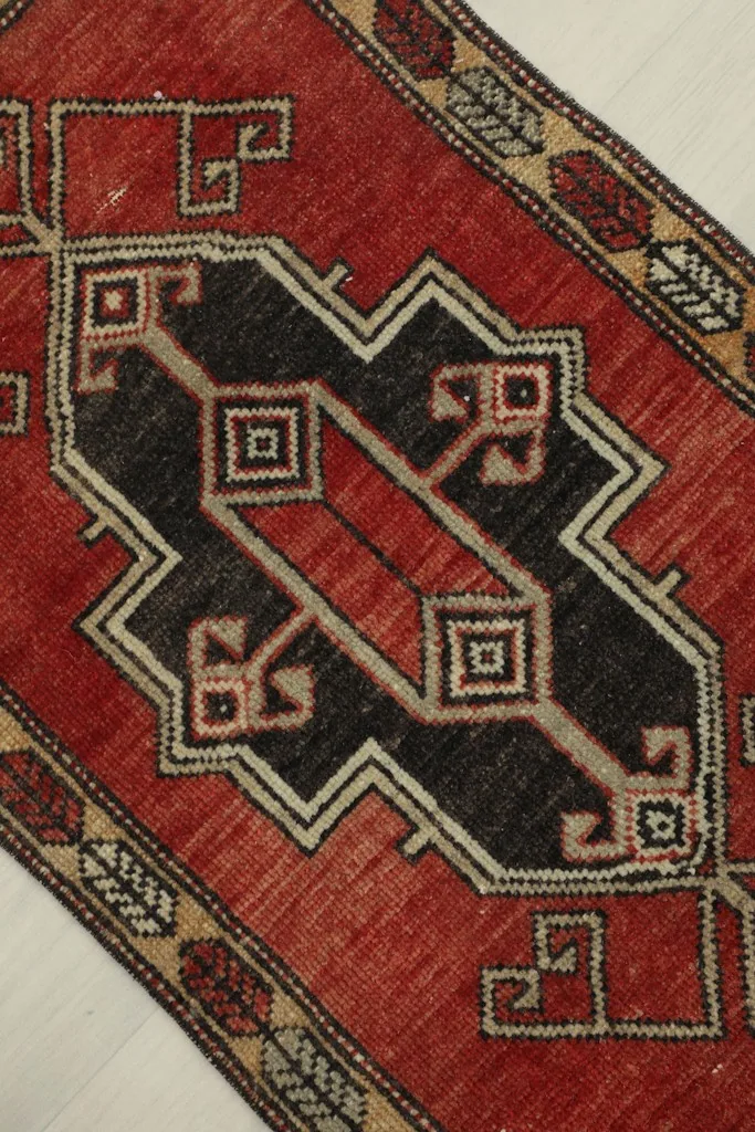 Angled close-up showing the central black geometric medallion and surrounding red field.