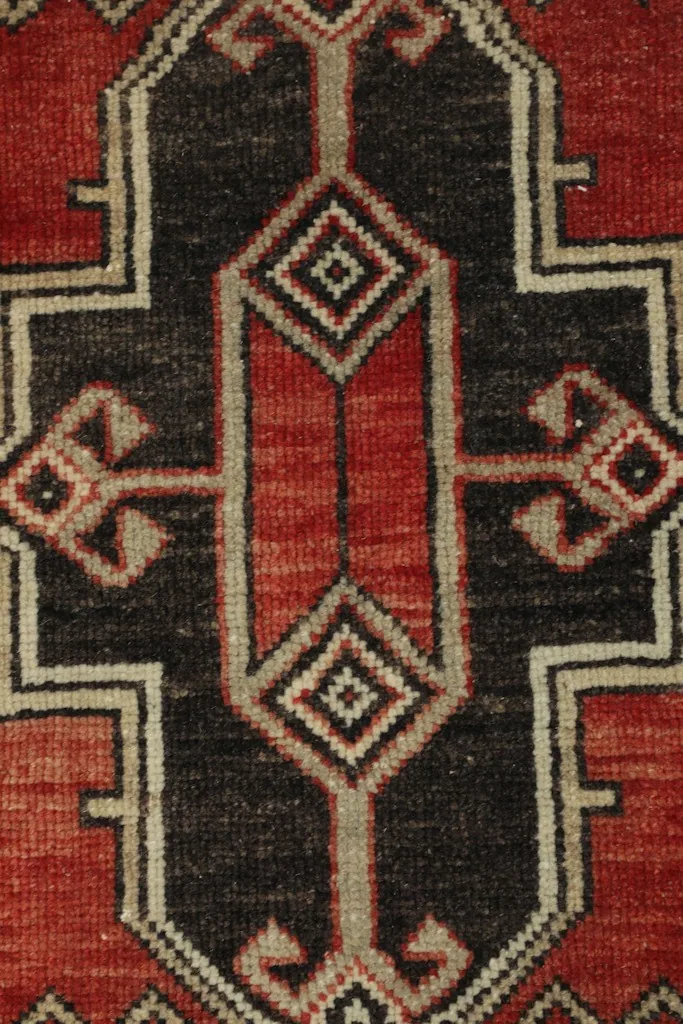Detailed view of the intricate central geometric medallion in black, red, and ivory.