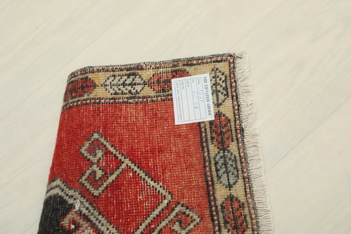 View of the rug's reverse side, showing the hand-knotted cotton foundation and a tag.