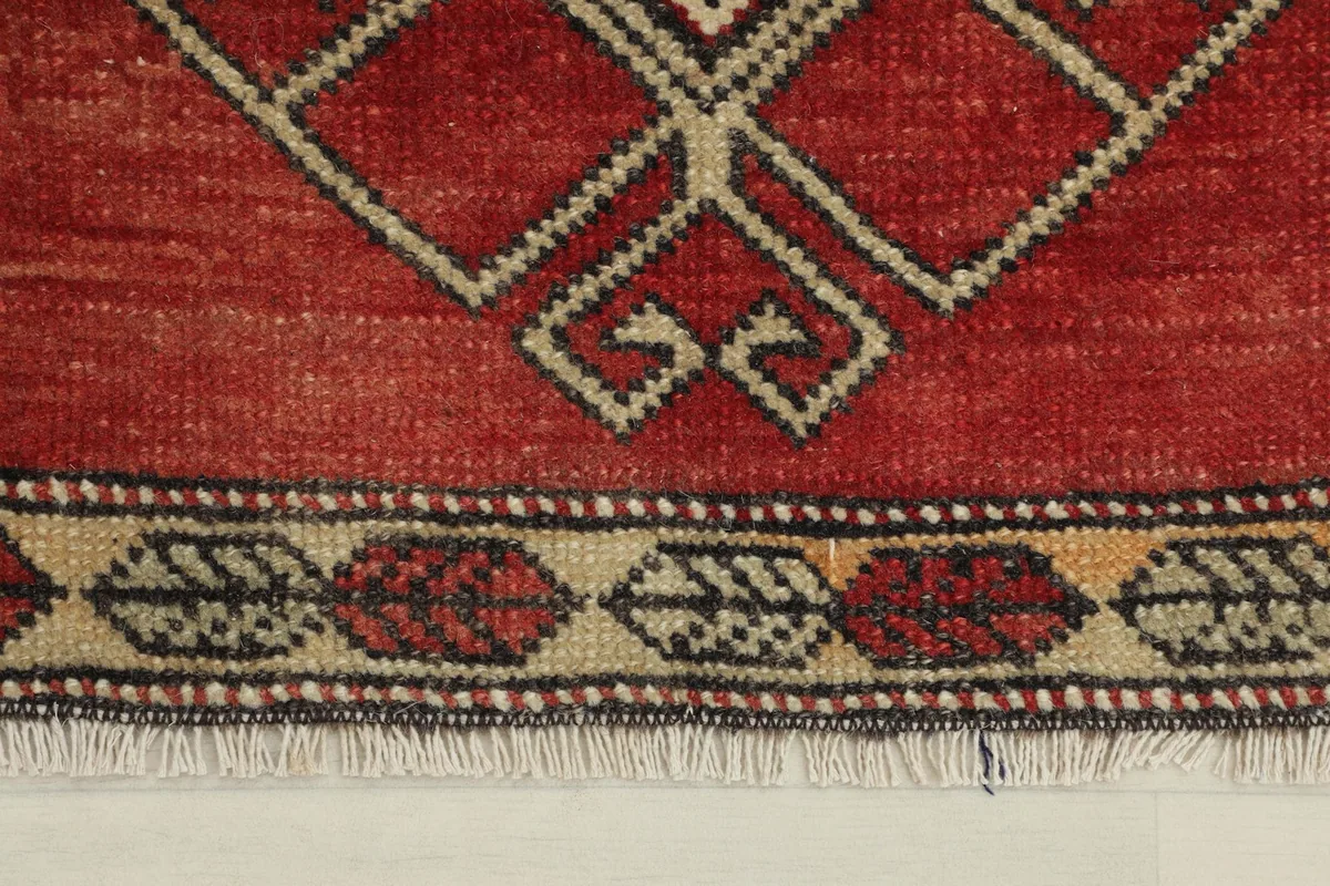 Close-up of the rug's lower border, showing the hand-knotted texture and minor wear.