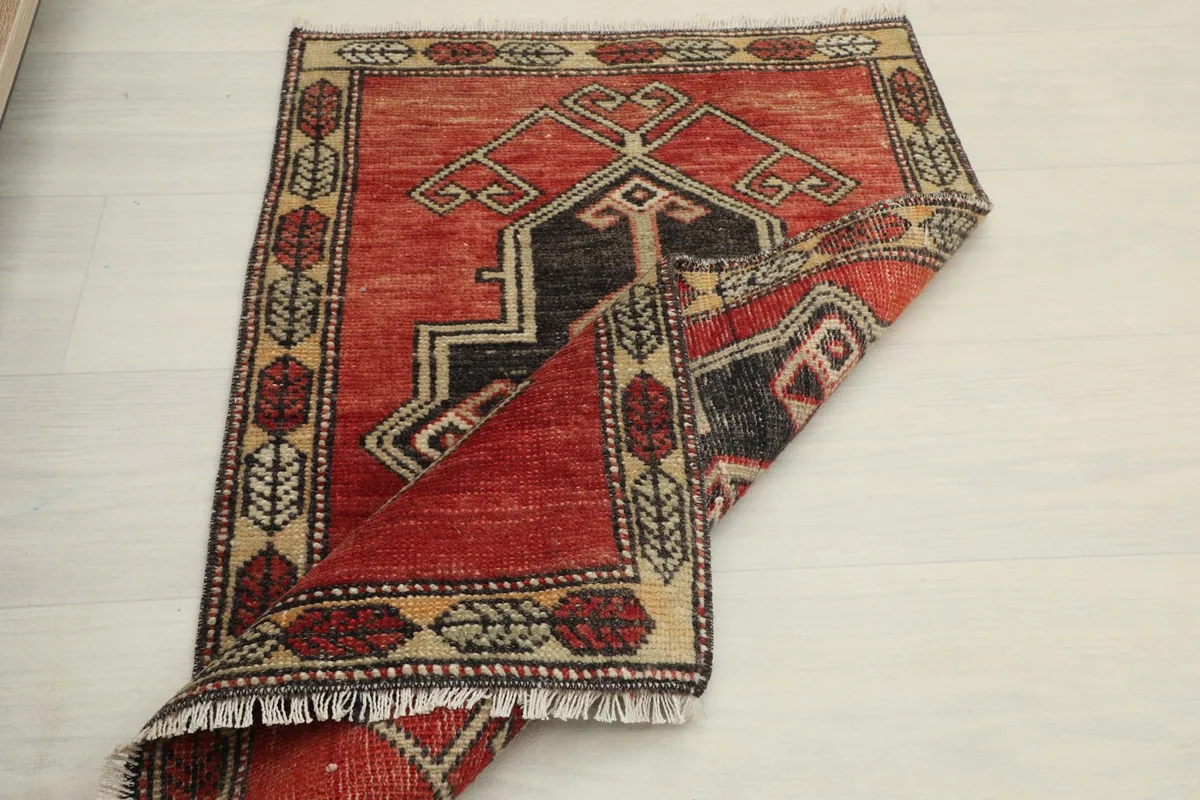 The rug folded over, displaying the full design and flexibility of the vintage textile.
