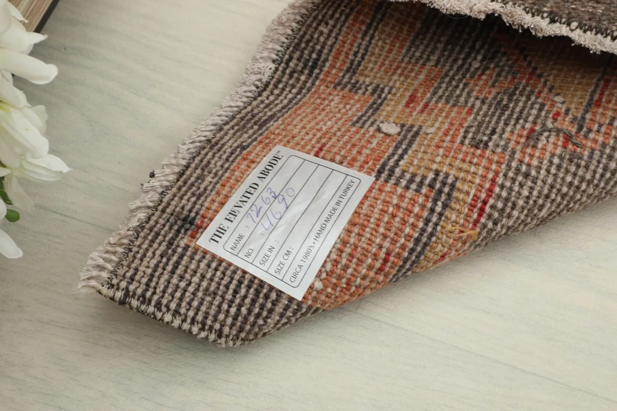 Close-up of the rug's reverse side with a label, showing the tight knotting of the wool pile.