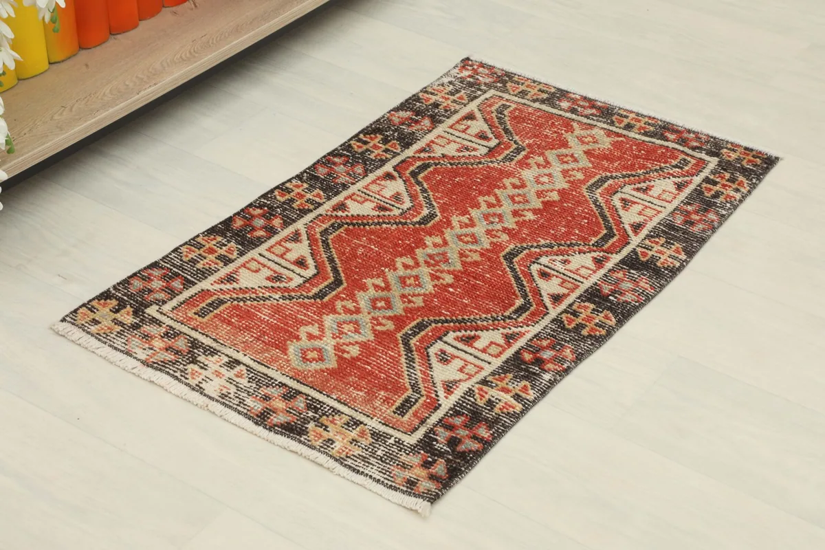 Angled view of the red and black geometric doormat on a light floor