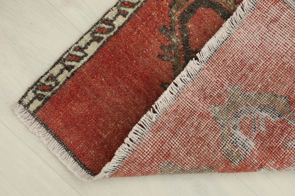 View of the back of the rug, folded to show the hand-knotted cotton foundation.
