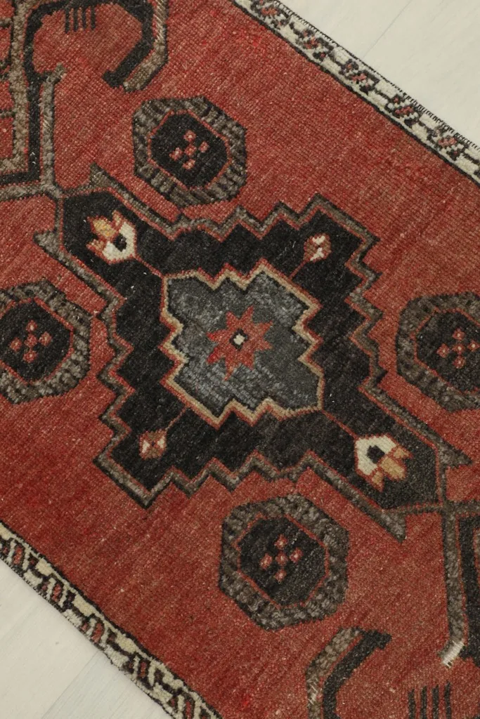 Overhead angled view highlighting the central black and gray geometric medallion and rust field.