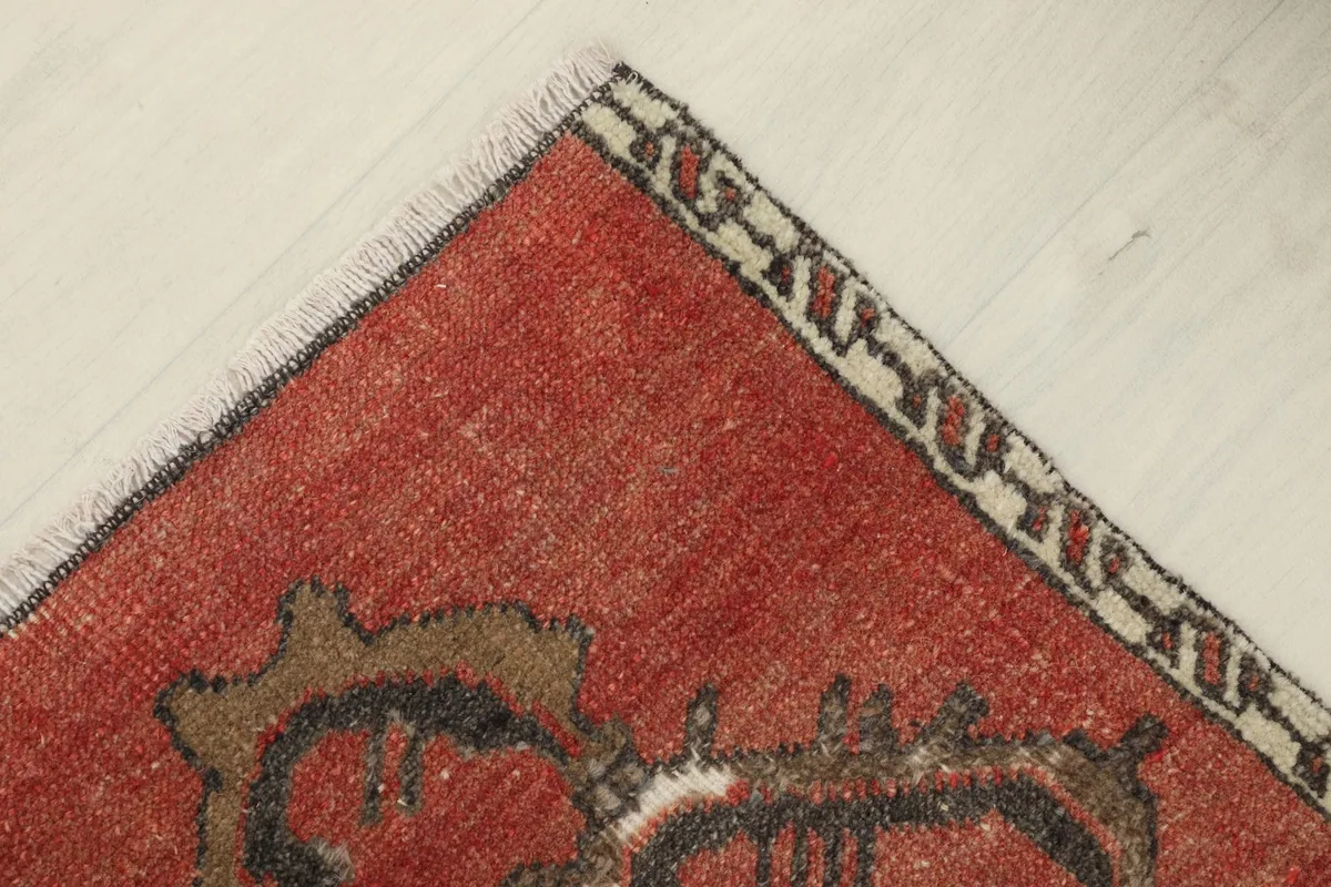 Top-down view of a corner of the rust doormat, highlighting the border and fringe.