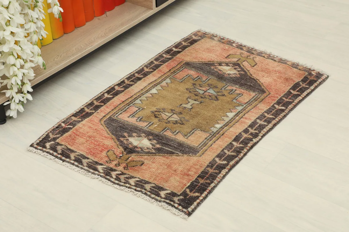 Angled view of the hand-knotted vintage rug, showing its rust field and charcoal border in a room setting.