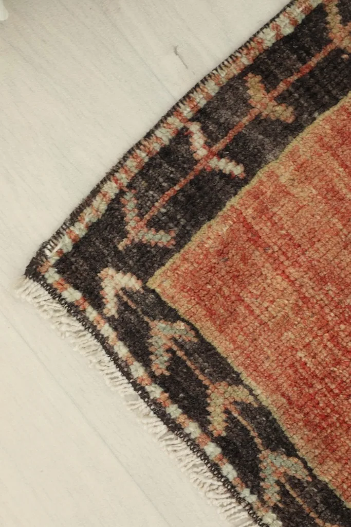 Angled view of a corner of the rug, emphasizing the border pattern and natural wear.