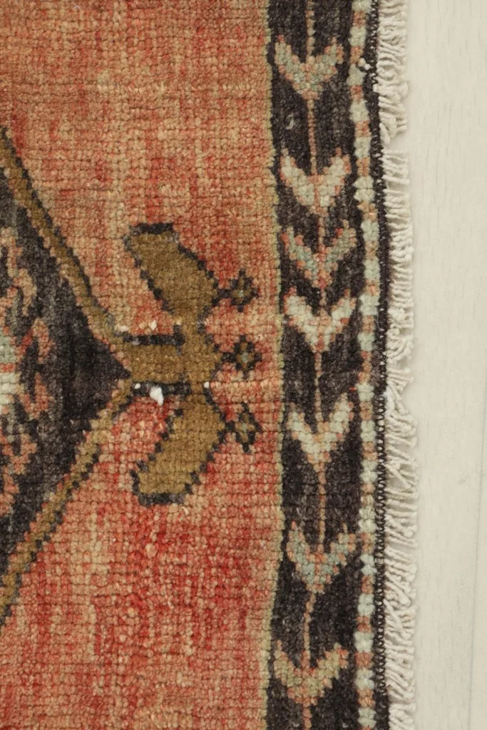 Close-up detail of the rust field and charcoal border with geometric patterns, showing the texture and fringe.