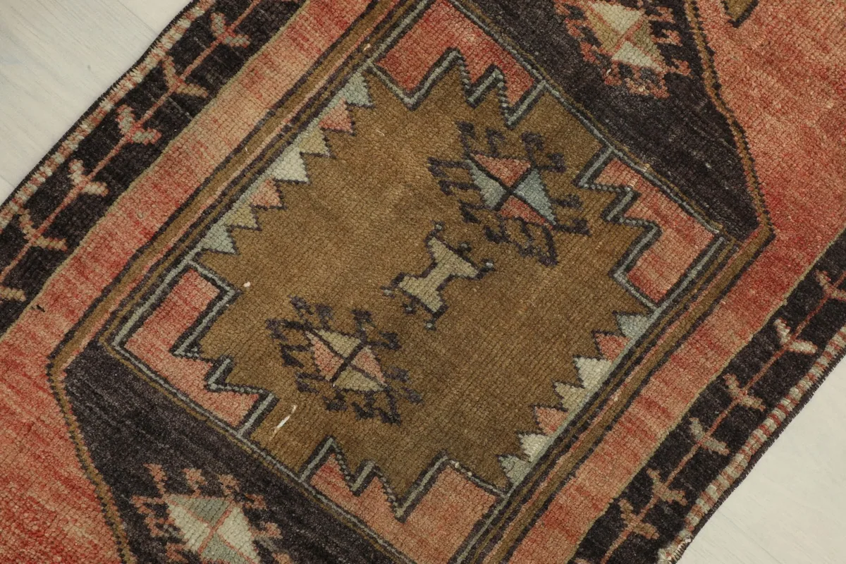Detailed view of the central brown medallion with geometric designs in blue, pink, and ivory tones.