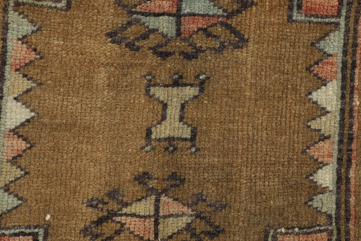 Close-up of the geometric motifs within the brown medallion, highlighting the wool pile and knotting.