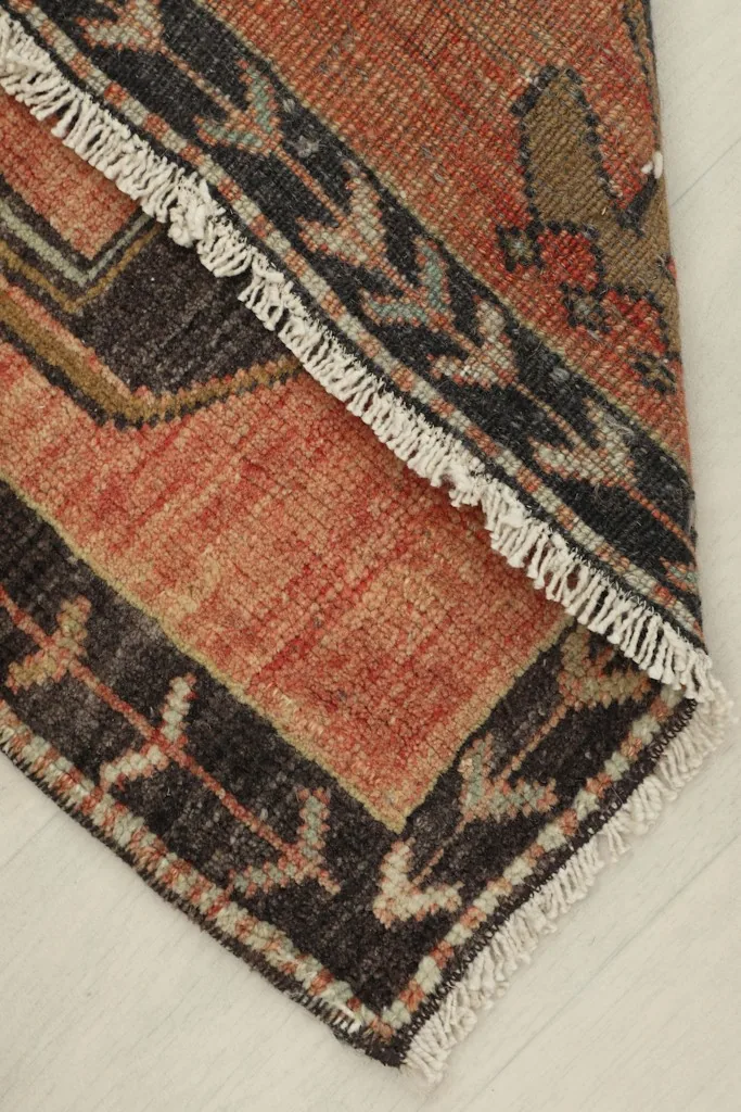 View of the rug folded to show the thickness of the material and the fringe along the edge.