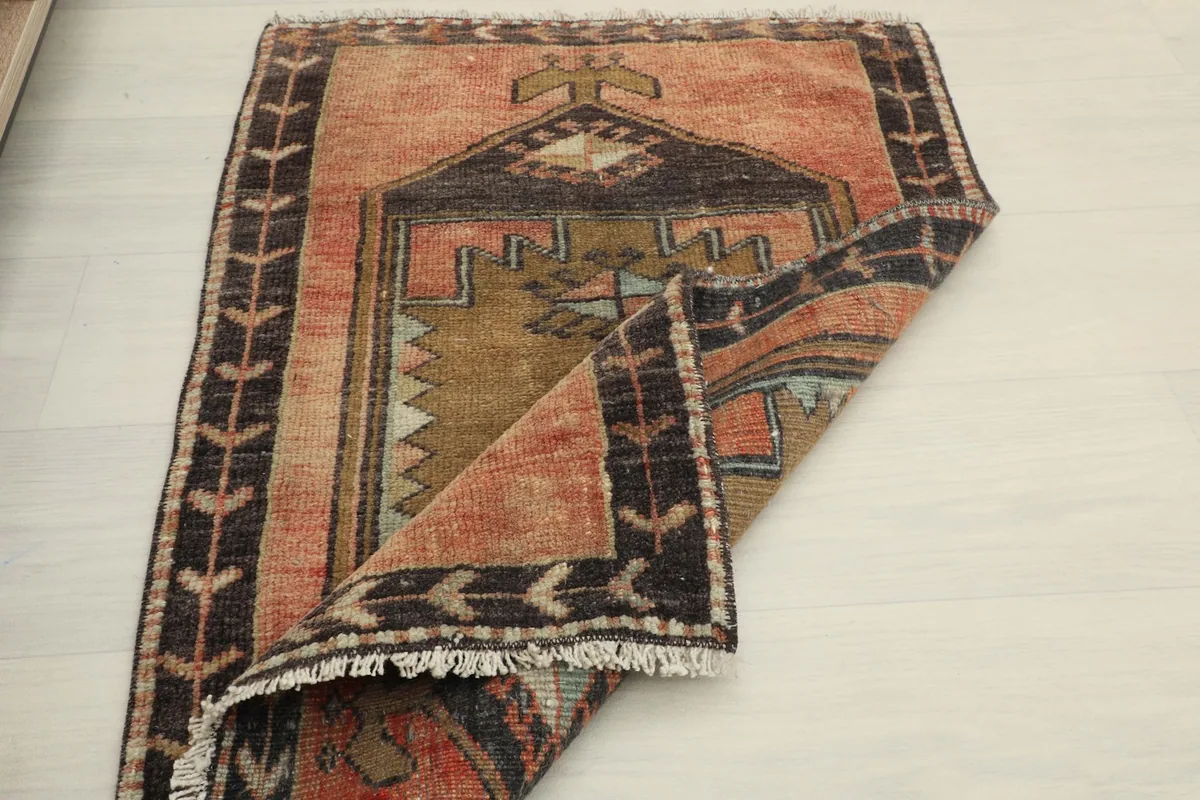 The vintage rug partially folded, showcasing its full design and the softness of the wool.