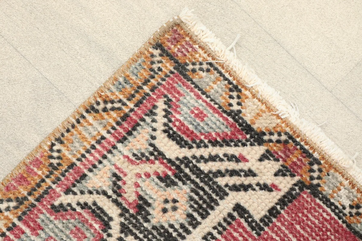 Corner detail showing the patterned border in tan, black, and rose surrounding the main field