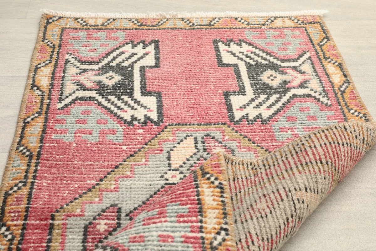 Angled view with a corner folded back, showing the back of the rug and the front pile