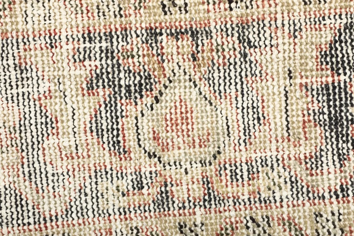 Macro detail of the low wool pile and intricate knotting, revealing beige, black, and rust threads.