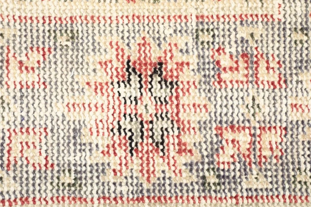 Close-up detail of the rug's wool pile, showing the intricate knotting and color blend of red, black, and gray.