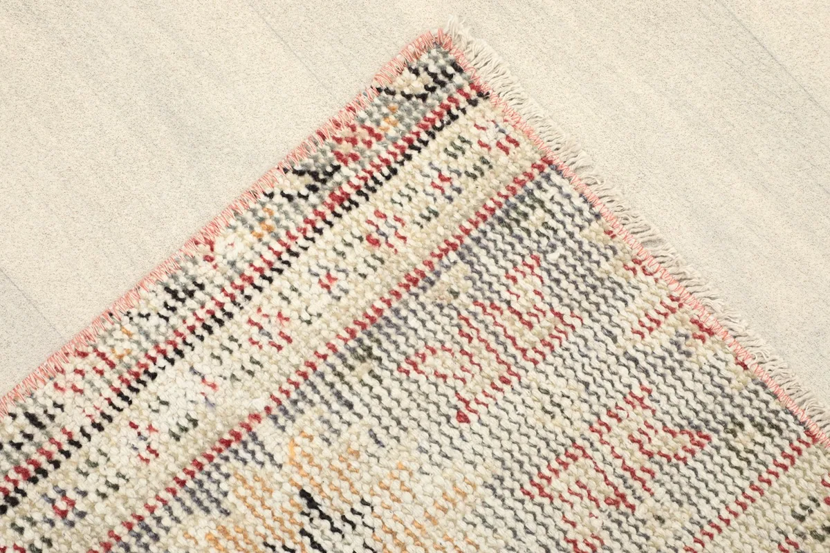 Corner detail of the rug, showcasing the faded rose border and geometric motifs.