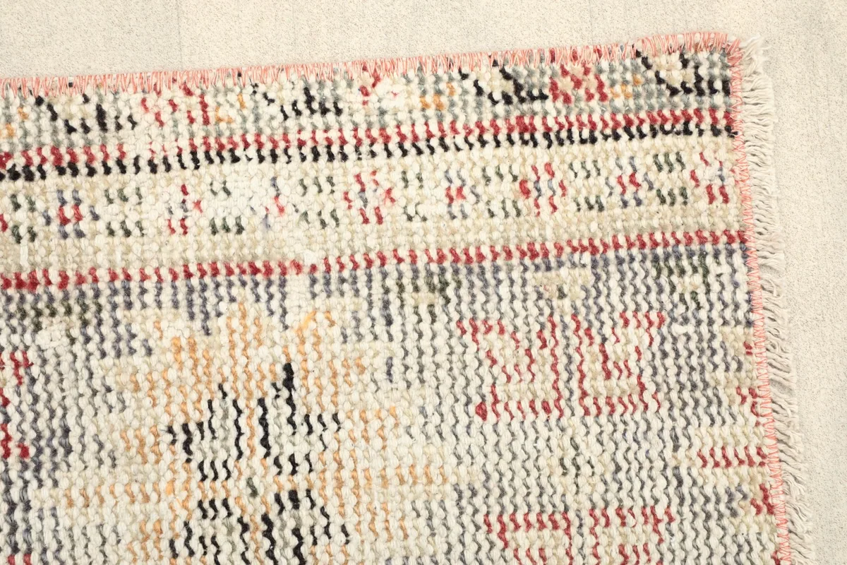 Close view of the rug's edge, revealing the short, dense wool pile and the subtle fringe.