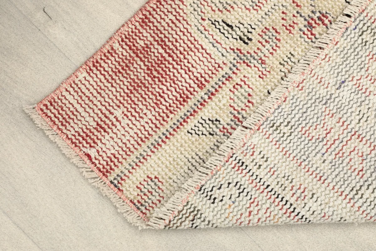 Partially folded rug displaying the texture of the wool pile and the cotton foundation.