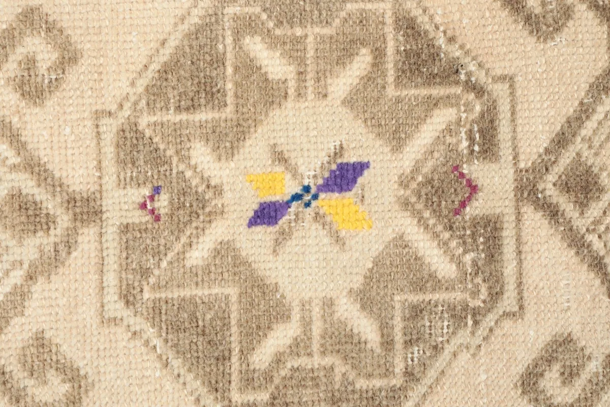 Close-up detail of the rug's central geometric medallion with small purple, yellow, and blue motifs.