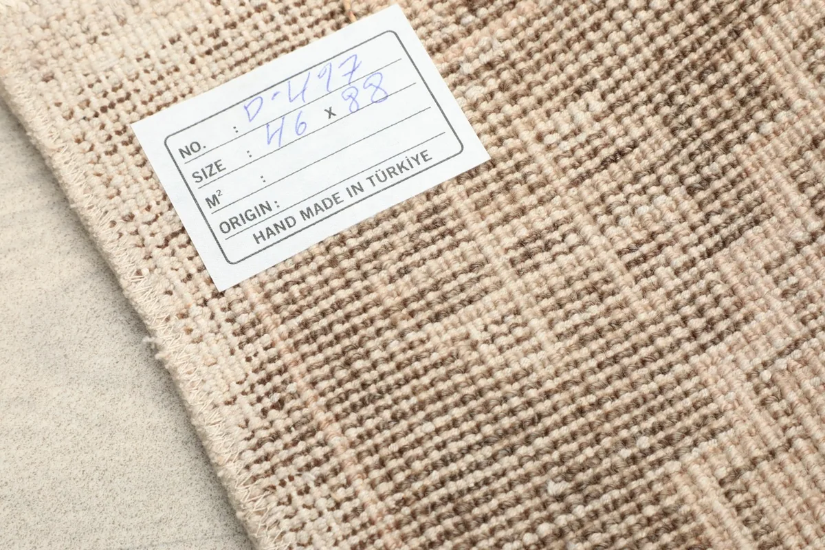 Back of the rug with a label, showing the tightly woven cotton foundation and hand-knotted knots.