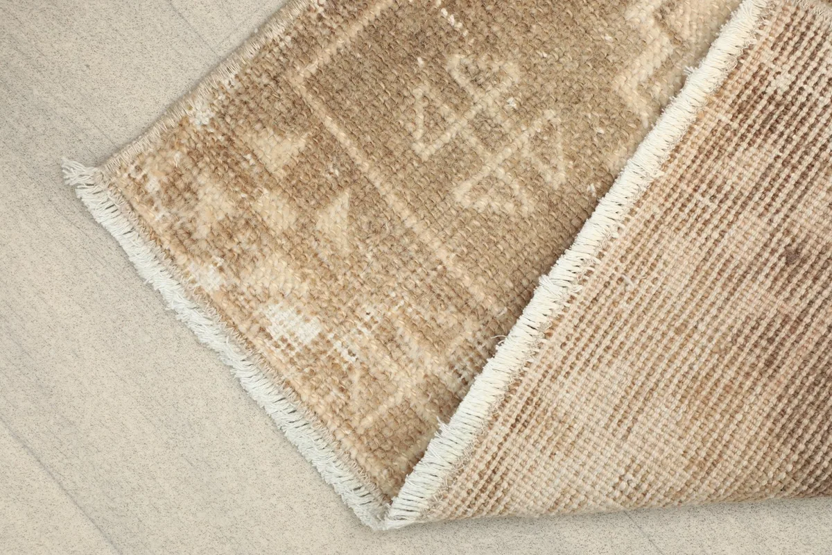 View of the rug folded to show the wool pile on cotton foundation and the reverse side texture.