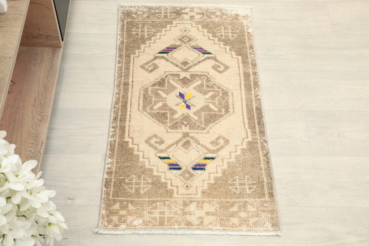 Overhead view of the ivory and tan vintage rug, highlighting its geometric patterns and colorful details.