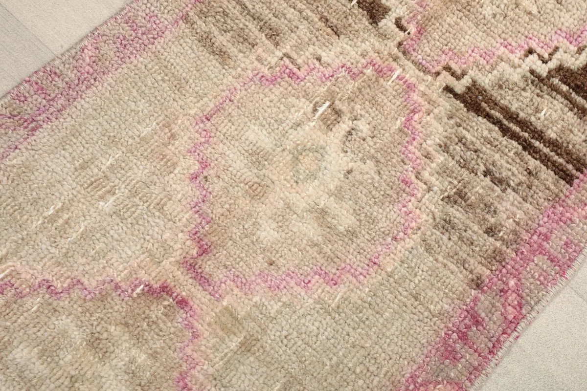 Close-up of the central geometric motif with pink outlines and beige field