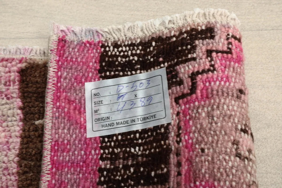 View of the rug's back, showcasing the cotton foundation and a size tag