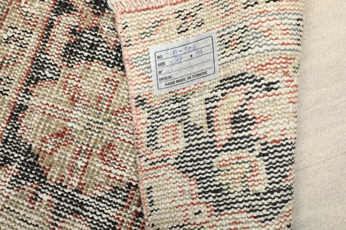 Close-up of the rug's back with a label, showing the hand-knotted quality and origin
