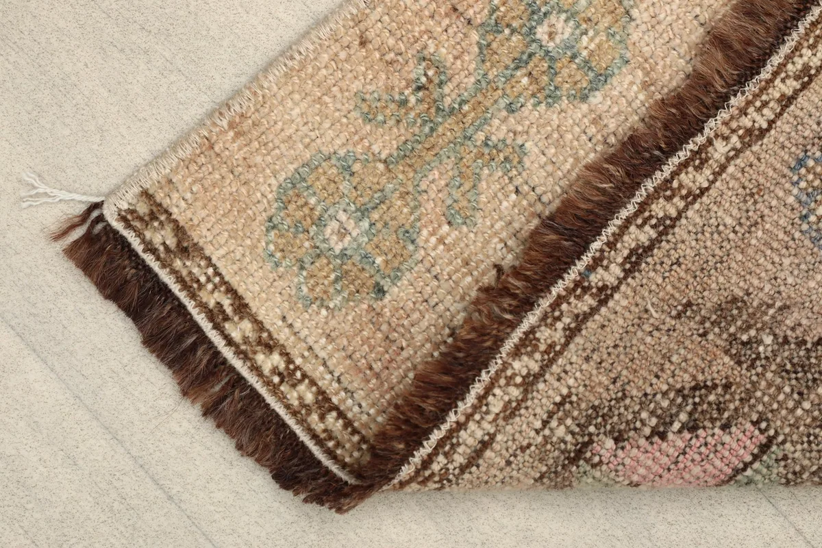 Angled view of the doormat, showing the short brown fringes and the texture of the hand-knotted wool.