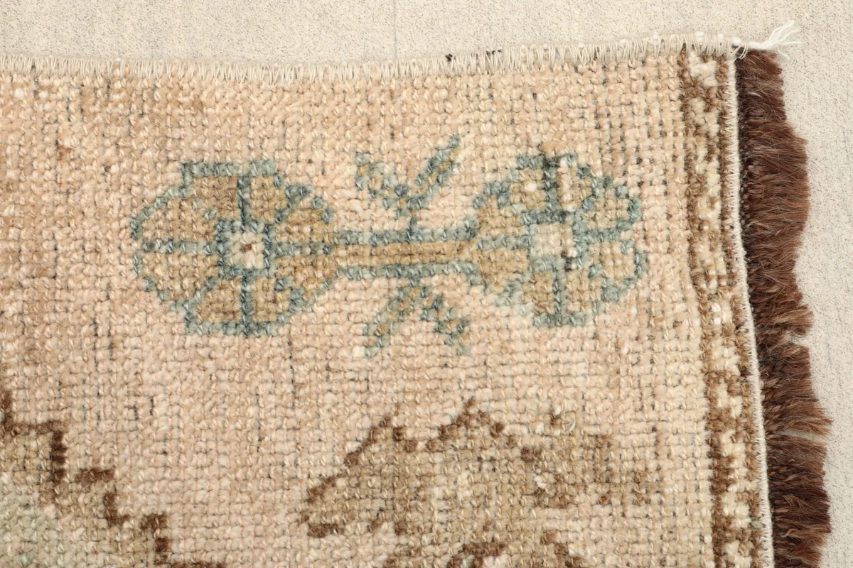 Detailed view of the olive and tan geometric patterns on the vintage doormat.