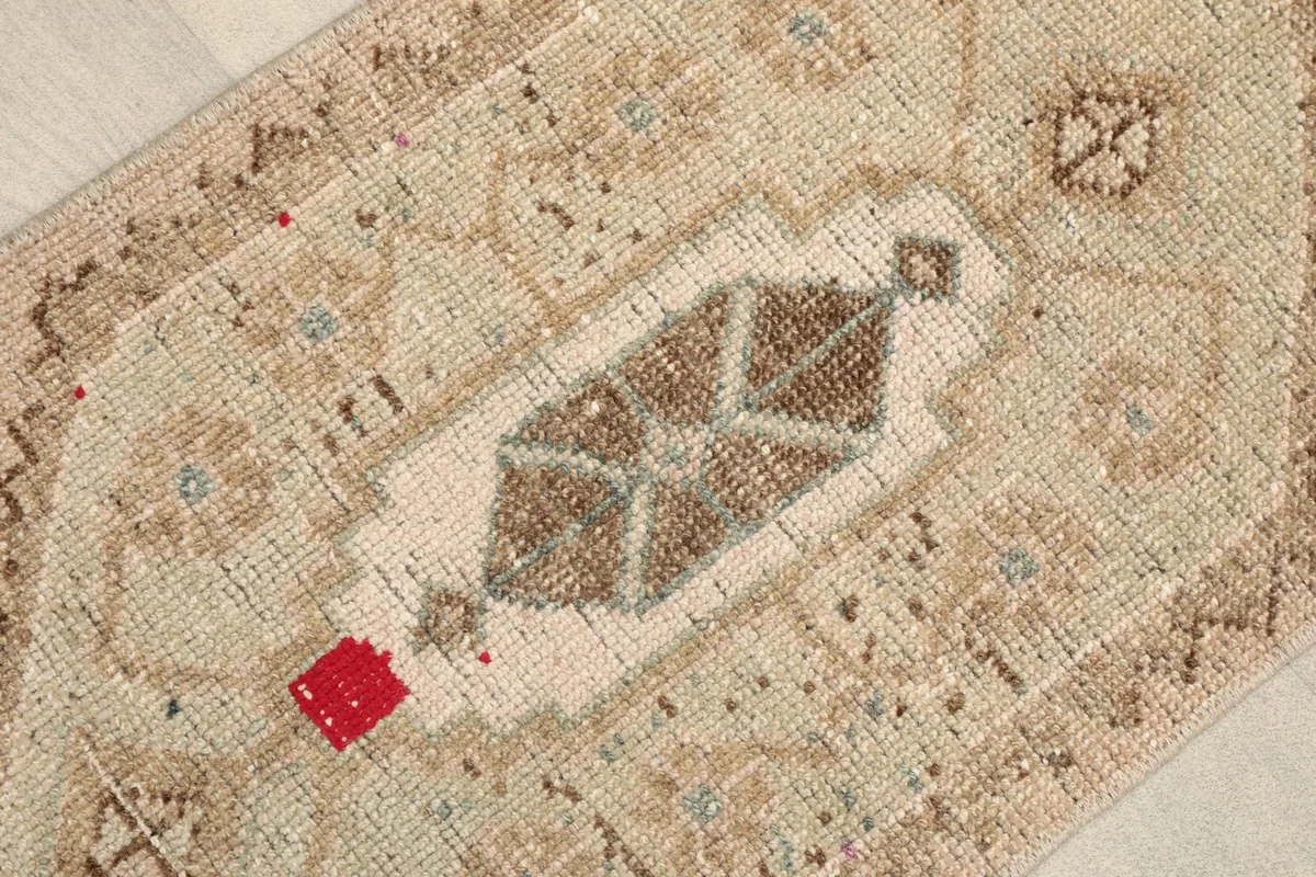 Close-up of the central geometric medallion with brown and olive accents, and a small red detail.