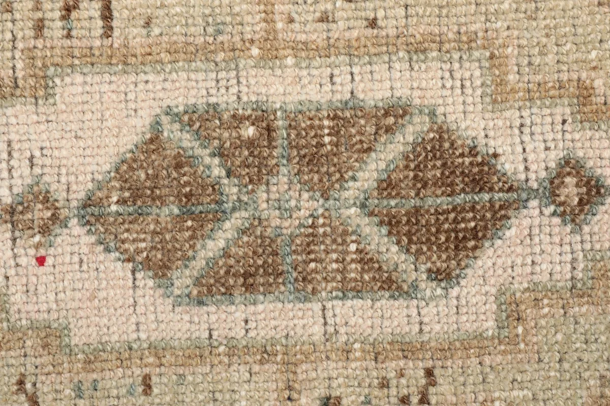 Macro detail of the central brown and olive geometric motif, highlighting the wool pile texture.