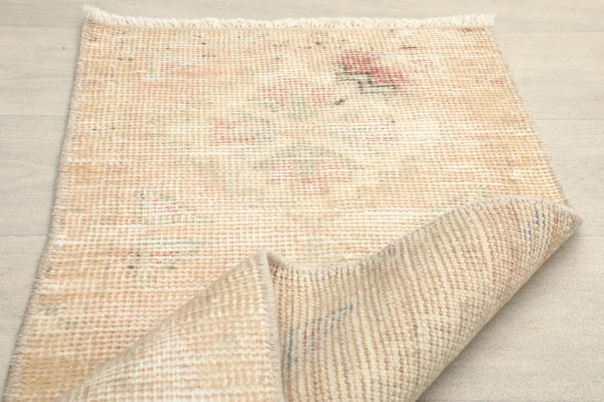 The rug partially folded, showing the flexibility and thickness of the vintage wool pile