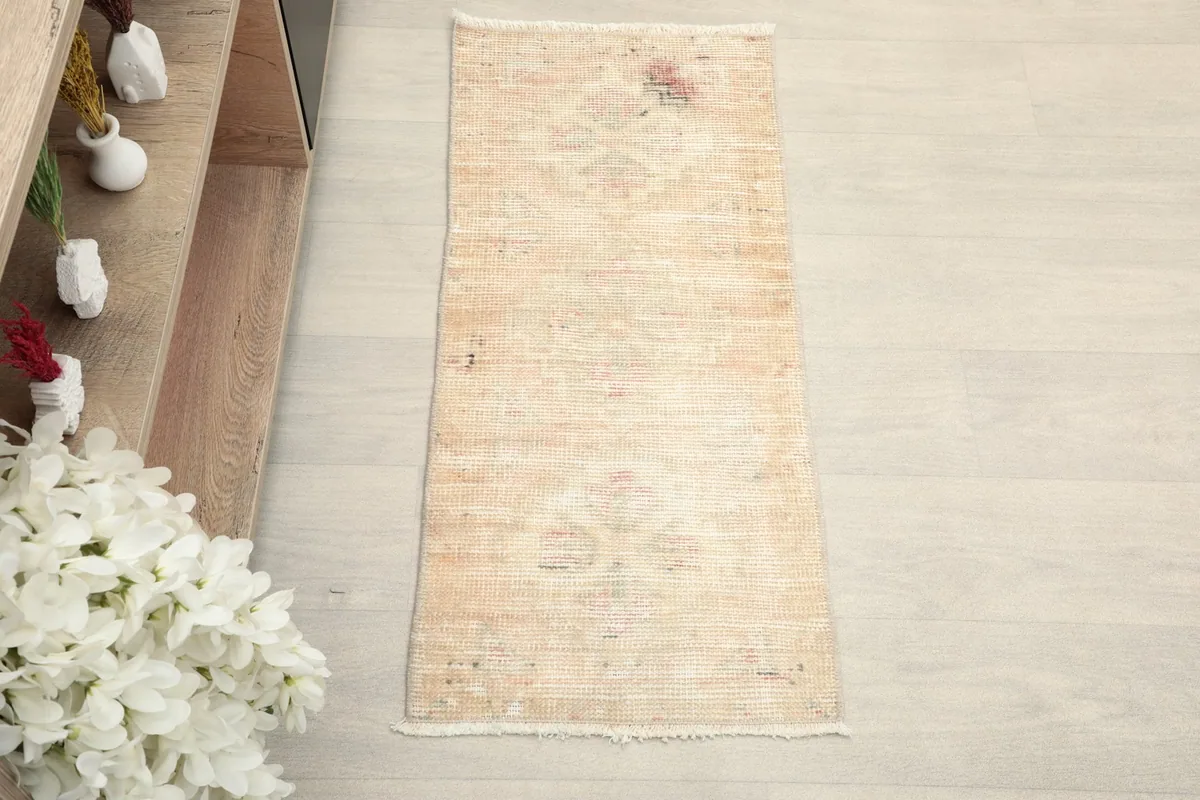 Overhead view of the beige and rose vintage rug, showcasing its rectangular shape and faded patterns