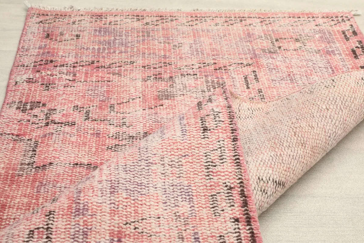Partial view of the rug's back, revealing the hand-knotted cotton foundation.