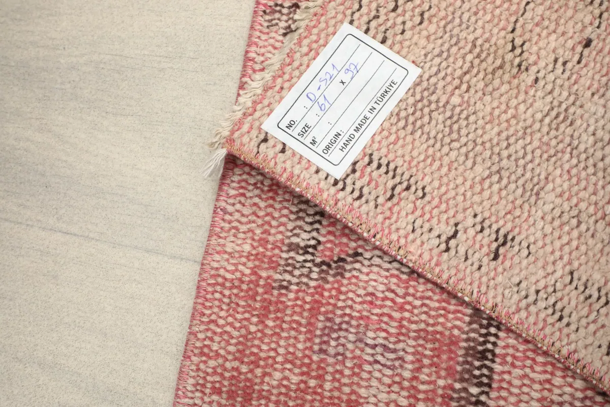 Close-up of the rug's back with a label, showing the tight knotting of the cotton foundation.