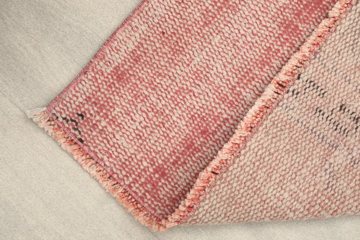 Rug corner folded to show the wool pile surface and the cotton foundation underneath.